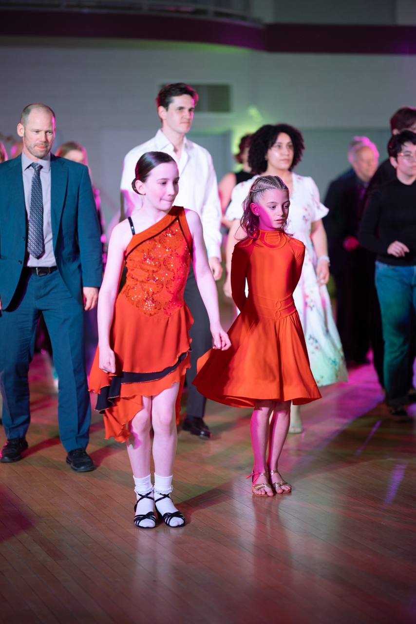 Young dancers joining the event floor in orange costumes