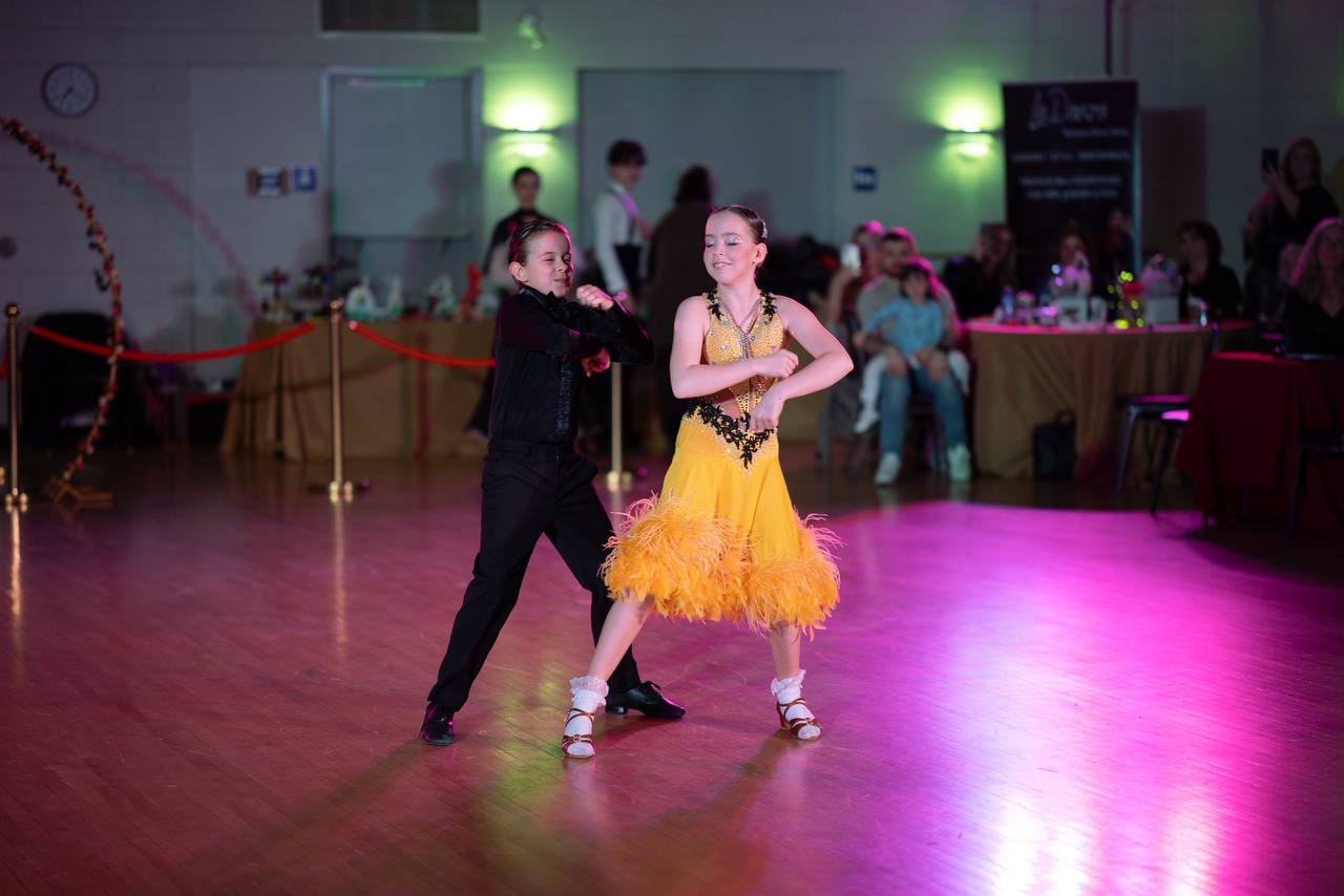 Young ballroom partners performing together in yellow and black